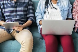 people on a couch on their laptop and tablets
