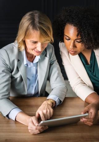 Two professional woman overlooking tablet