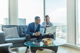 Two men in a high rise apartment looking at a computer