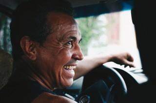 Middle aged man driving car and looking over at passenger