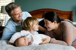a family of four hanging out on a bed