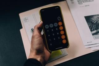 Woman holding phone and using calculator