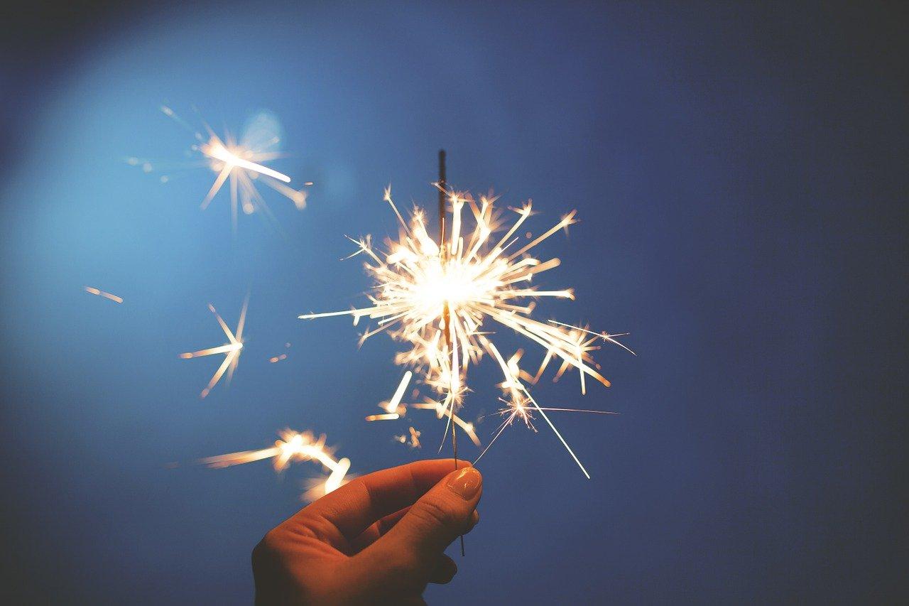 a hand holding a lit sparkler