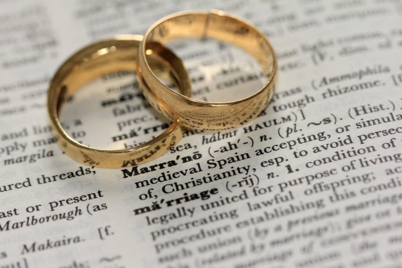 two rings sitting on a open dictionary over the word marriage