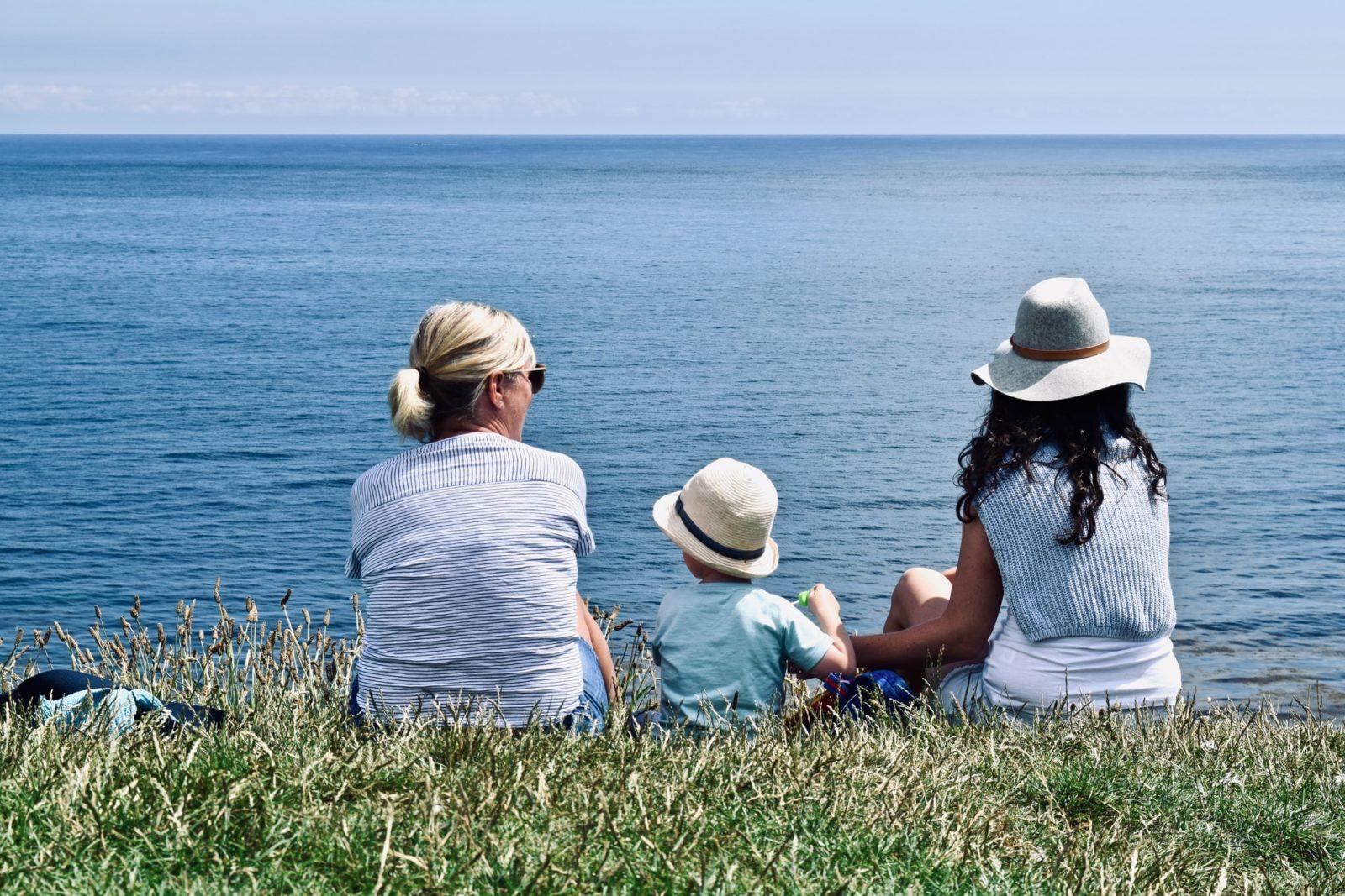 mom, grandma and daughter looking out at an ocean