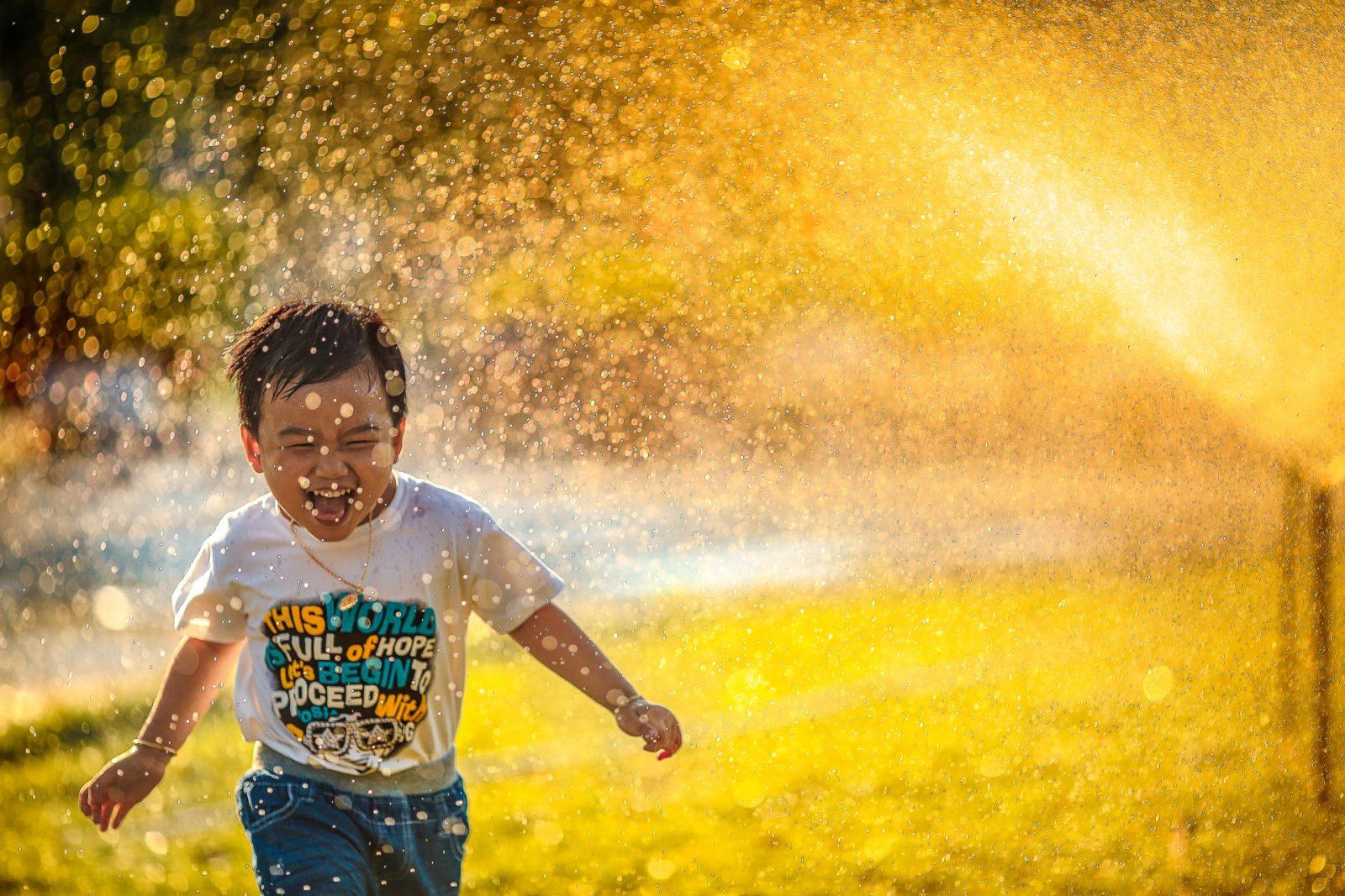 a child running in a sprinkler outside