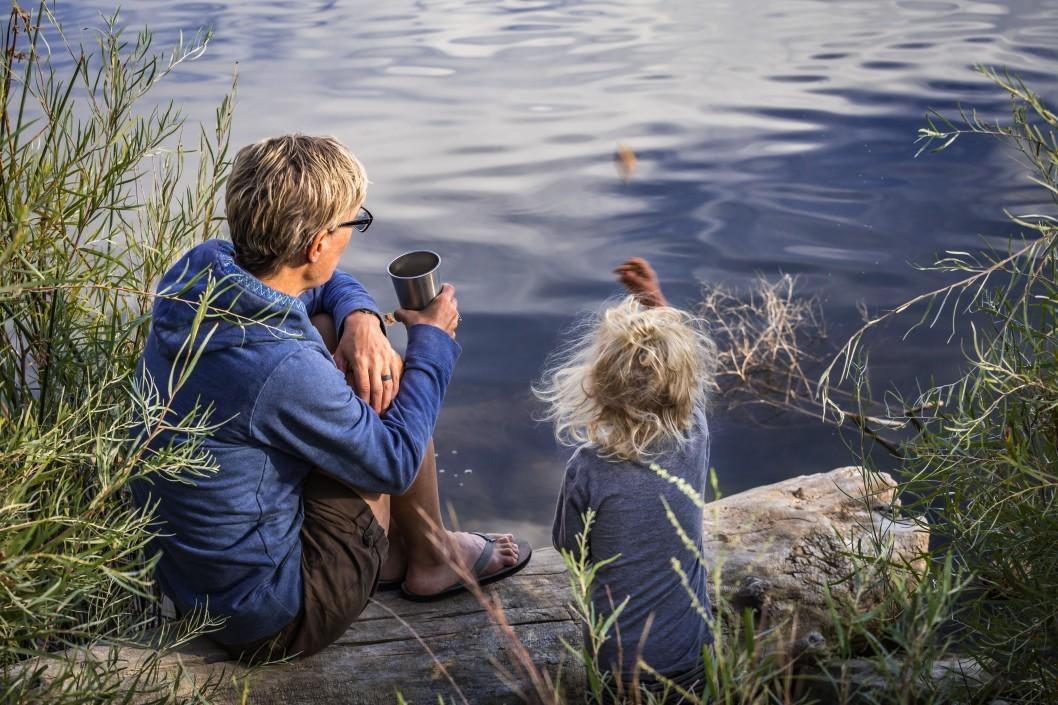 a grandmother sitting with her grandaughter on a rock by a lake