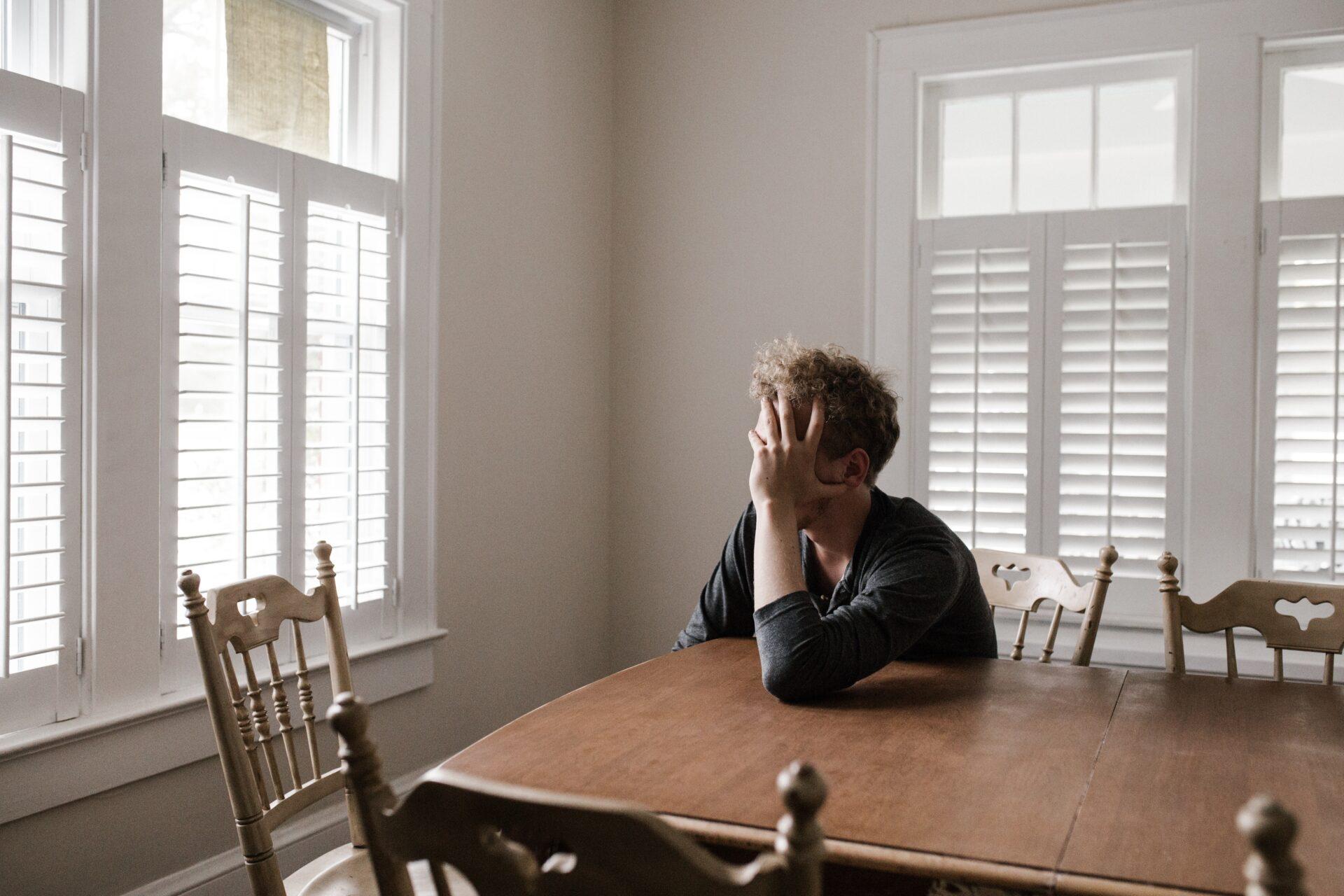 Man sitting at a table with his head in his hands