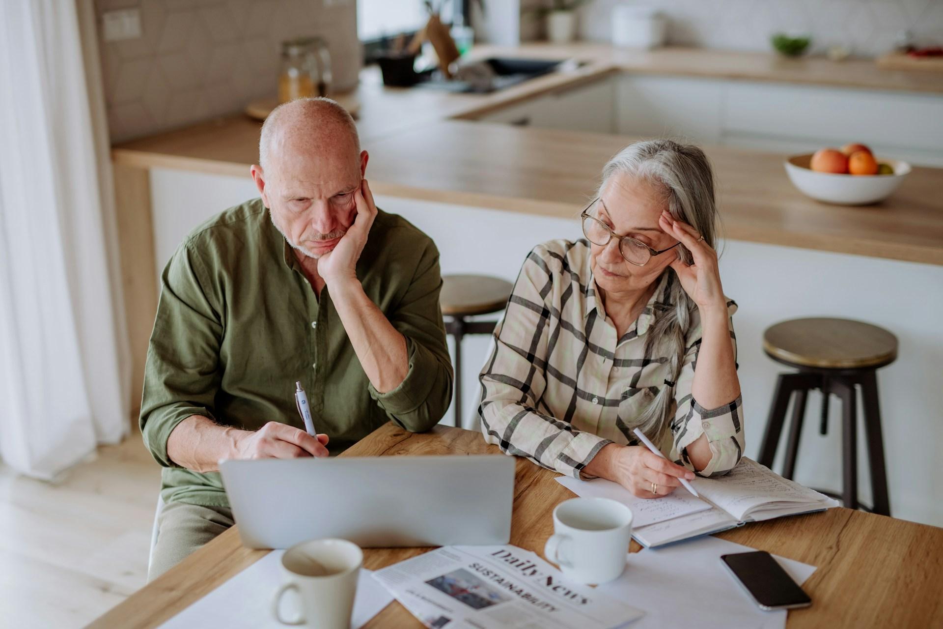 couple in kitchen reviewing plans on laptop